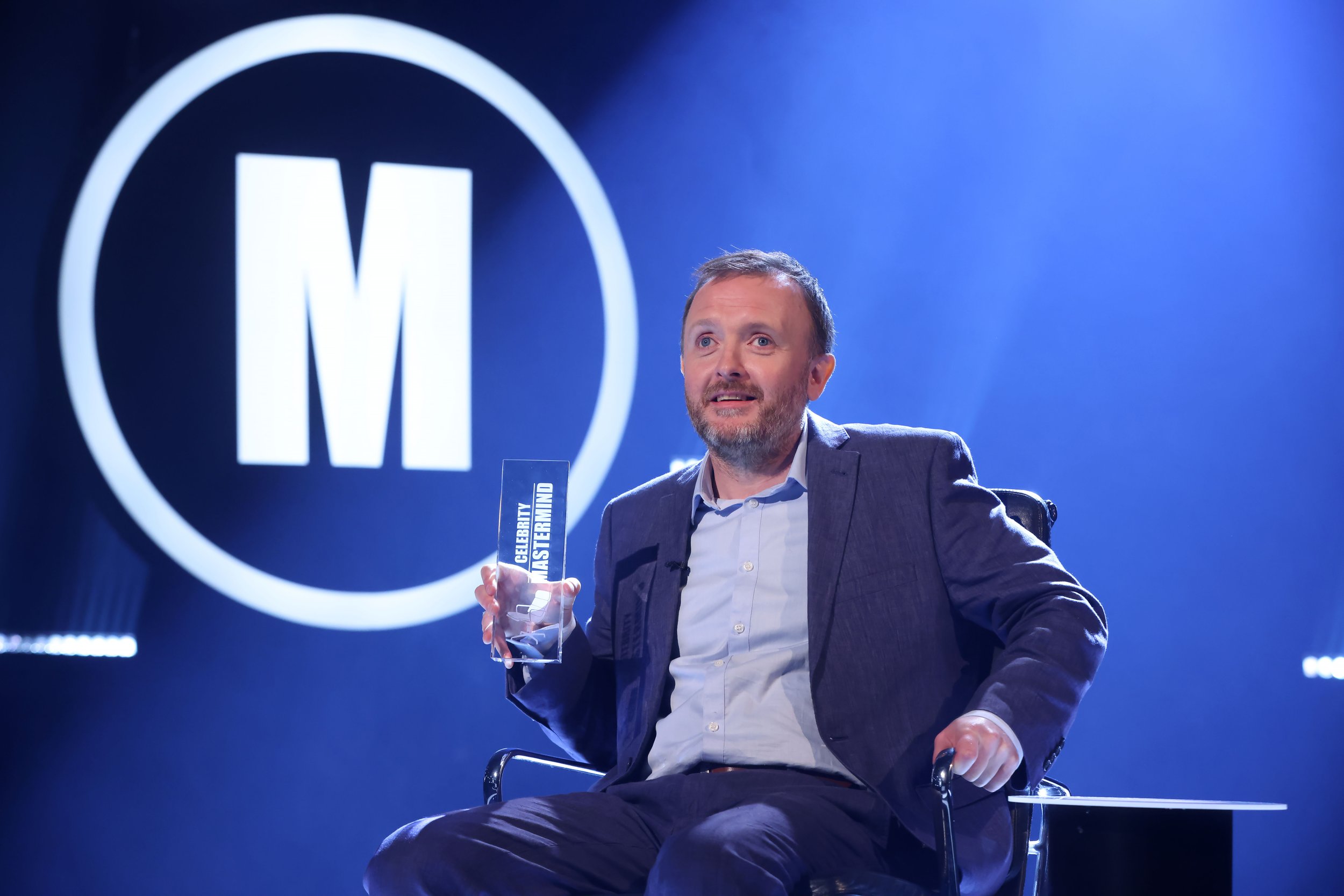 RX10-050-Chris-McCausland-Trophy-in-chair-EMBARGO